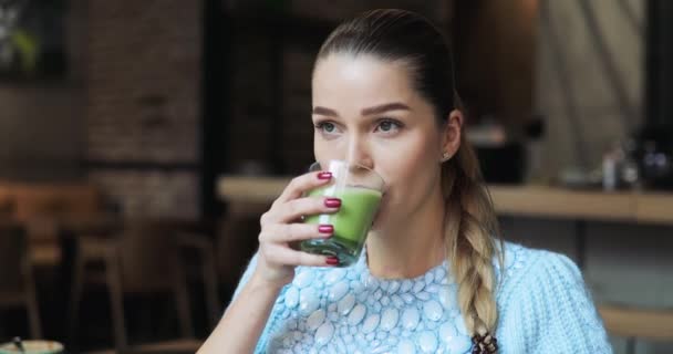 Улыбающаяся женщина пьет маття латте в кафе — стоковое видео