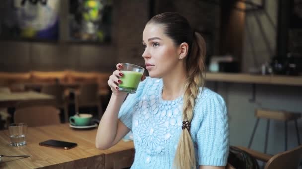 Mujer bebiendo matcha latte en la cafetería — Vídeo de stock