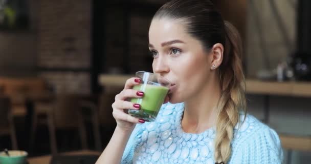 Mujer sonriente bebiendo matcha latte en la cafetería — Vídeos de Stock