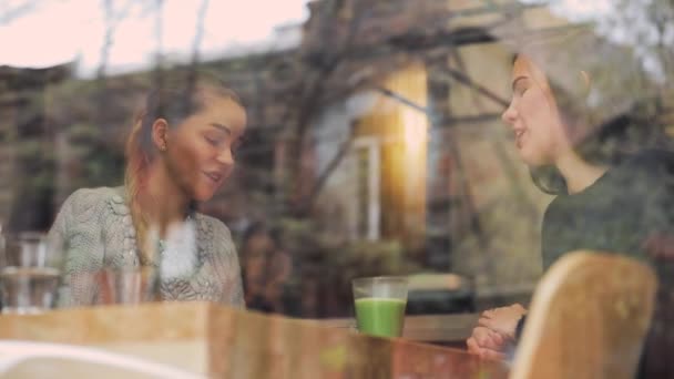 Freundinnen unterhalten sich in einem Café hinter dem Fenster — Stockvideo