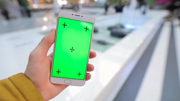 Mannelijke hand met smartphone met groen scherm in winkelcentrum — Stockvideo