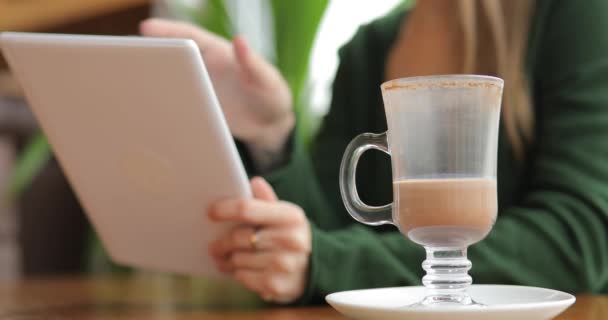 Mulher usando tablet dispositivo PC no café, xícara de bebida de cacau em primeiro plano — Vídeo de Stock