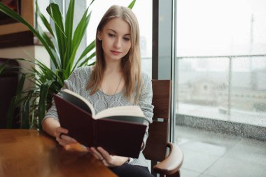 Kafede kitap okuyan kadın.