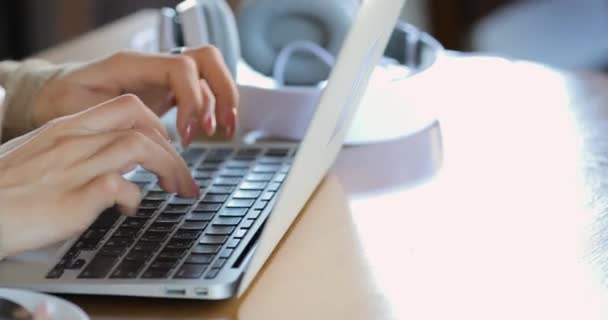 Молодая женщина-блогер, работающая на ноутбуке в кафе крупным планом, печатает описание для своего видео — стоковое видео