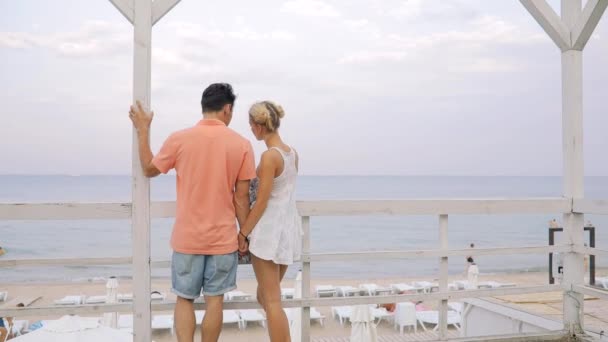 Liefde voor jong koppel op de kust van de zee die hand in hand — Stockvideo