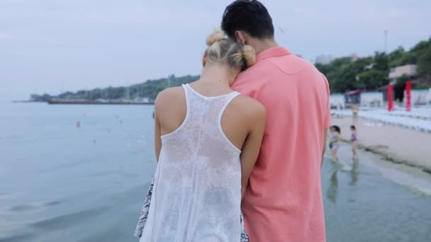 Casal jovem abraçando uns aos outros olhando para a costa do mar com gaivotas voadoras — Vídeo de Stock