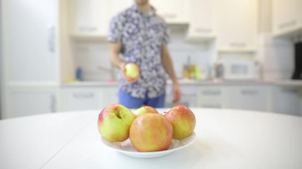 Onherkenbaar man nemen van verse schone apple van bord en eten — Stockvideo