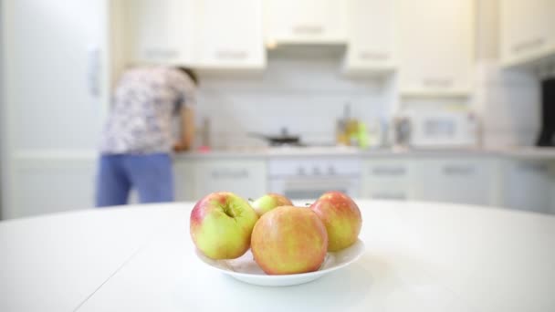 認識できない人は、テーブルの上にプレートで新鮮なきれいなリンゴを置く — ストック動画