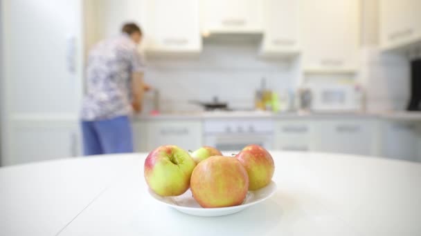 Hombre irreconocible poner manzana limpia fresca en el plato sobre la mesa — Vídeos de Stock