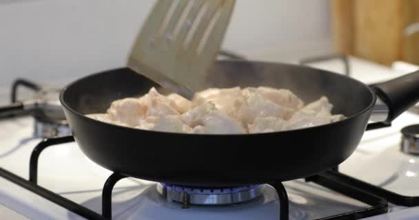 Preparación de la carne de pollo en una sartén de primer plano, mezclando con cuchara de madera — Vídeos de Stock