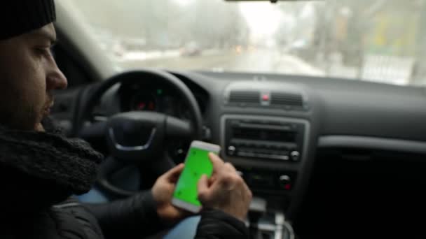 Uomo dimostrando schermo verde vuoto di smartphone in auto, chiave cromatica — Video Stock