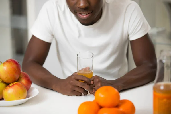 African american man drinking juice in kitchen