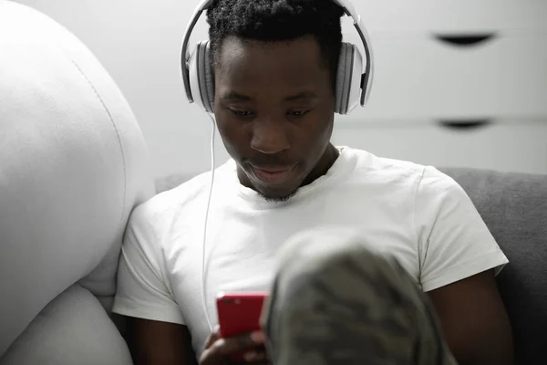 African man listening to music at home in headphones