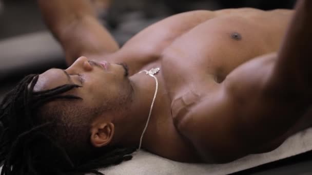 Hombre afroamericano bombeando músculos con mancuernas en el gimnasio — Vídeo de stock