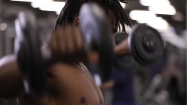 Afrika kökenli Amerikalı adam bir jimnastik salonu kas dumbbells ile pompalama