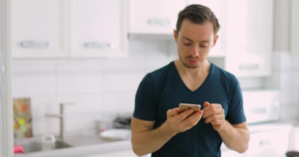 Uomo sorpreso che mostra lo schermo verde vuoto dello smartphone a casa con i pollici in su — Video Stock