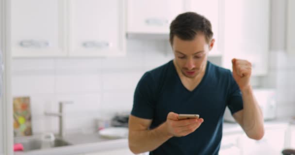 Feliz homem da sorte mostrando a tela verde vazia do telefone inteligente em casa — Vídeo de Stock