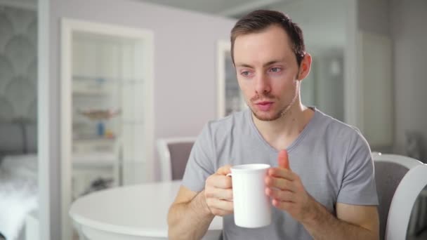 Joven solo bebiendo té caliente en casa cocina con buen humor — Vídeos de Stock