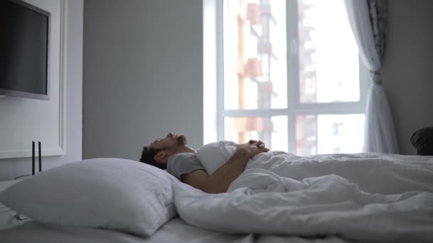 Mal sueño, el hombre se despierta bruscamente en su cama — Vídeo de stock