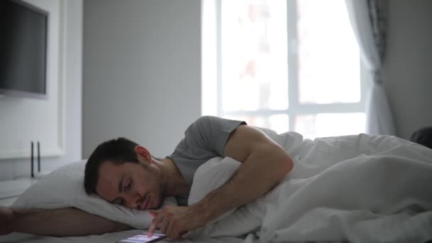 Uomo sdraiato nel suo letto con il cellulare — Video Stock