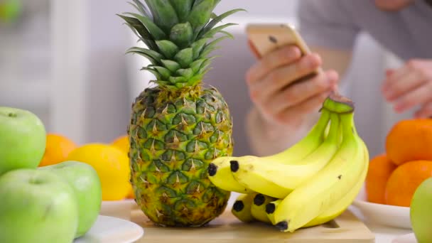 Неузнаваемый человек фотографирует ананас на фруктовом столе — стоковое видео