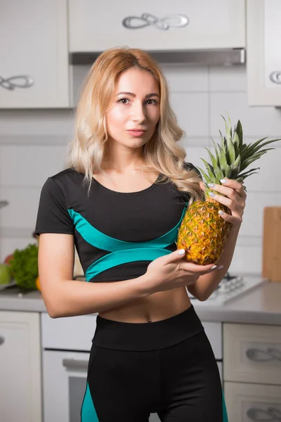 Sports woman holding pineapple on kitchen, healthy food diet concept