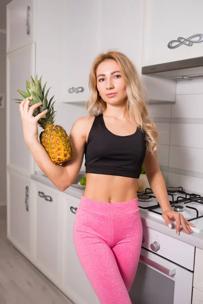 Sexy Mulher Esportiva Leggins Rosa Cozinha Segurando Abacaxi — Fotografia de Stock