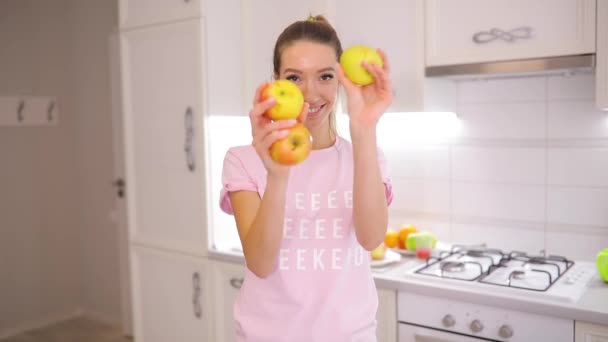 Беззаботное утро выходного дня, женщина жонглирует яблоками на кухне дома — стоковое видео
