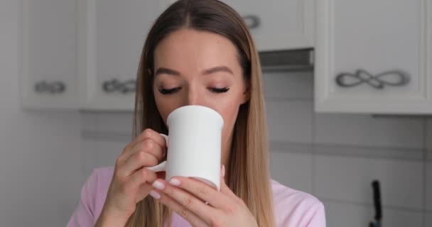 Mujer joven en camiseta rosa disfrutar de beber té con galletas de invierno en casa — Vídeos de Stock