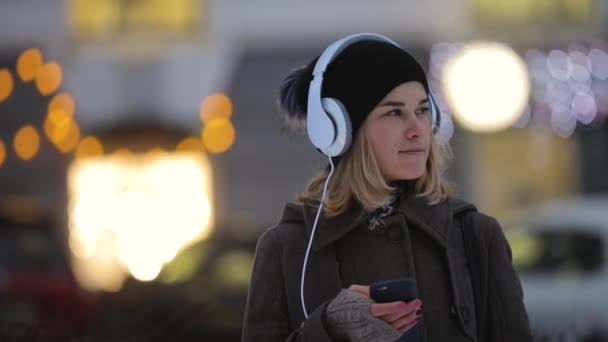 Winter, Frau denkt und schreibt Nachricht in ihr Smartphone in der Abendstadt — Stockvideo