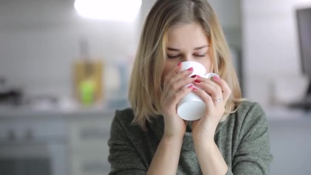 Jeune femme buvant du thé à la maison cuisine — Video