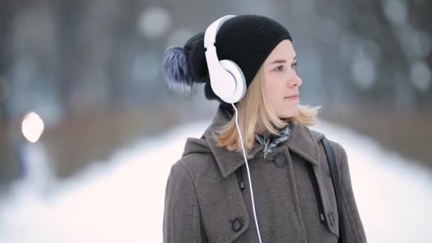 Mujer escuchando música en auriculares en la ciudad de invierno — Vídeo de stock