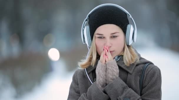 Vrouw luisteren naar muziek in hoofdtelefoons in winter city — Stockvideo