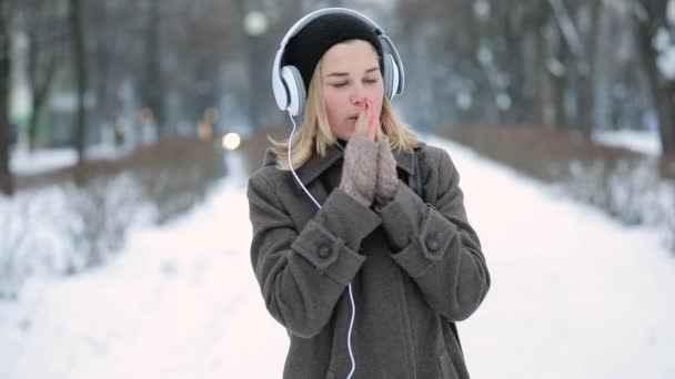 Vrouw luisteren naar muziek in hoofdtelefoons in winter city — Stockvideo