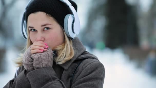 Женщина слушает музыку в наушниках в зимнем городе — стоковое видео