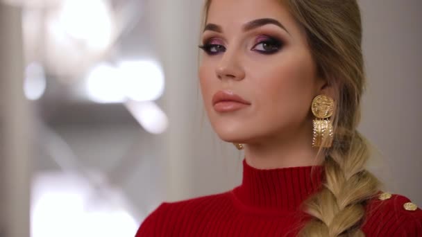 schönes Mode-Model in rotem Kleid posiert mit Ohrringen, perfektes Make-up im Gesicht