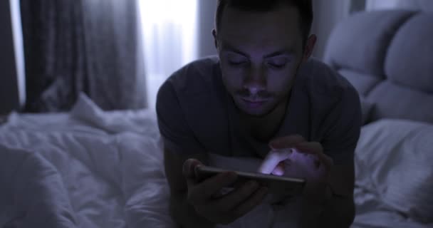 Homem na cama com smartphone à noite antes de dormir — Vídeo de Stock