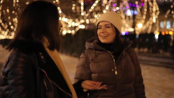 Щасливі дівчата гуляють по нічній алеї, прикрашеній гірляндою і розмовляють — стокове відео