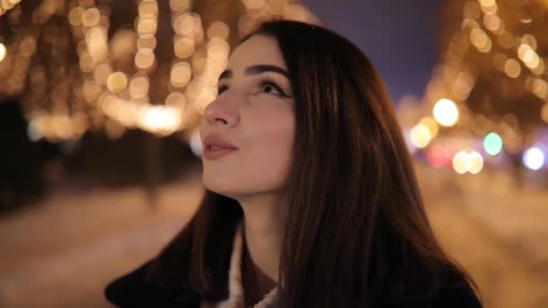 Женщина смотрит на красивый прекрасный ночной переулок, украшенный желтыми гирляндами светимости — стоковое видео