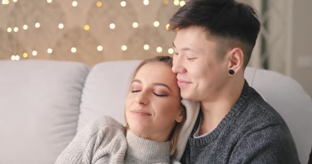 Любов, молода пара обіймається на дивані вдома — стокове відео