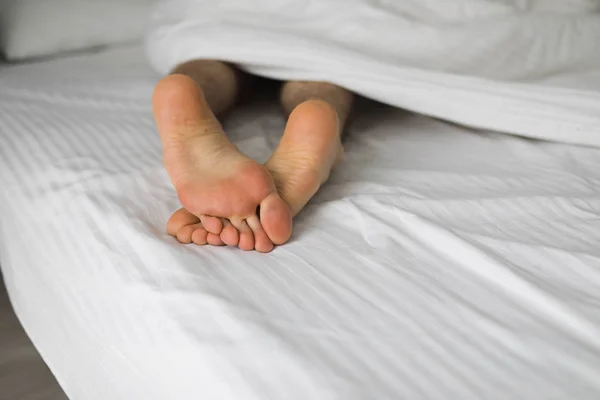 Battaniyenin Altında Beyaz Bir Yatakta Erkek Ayağı — Stok fotoğraf