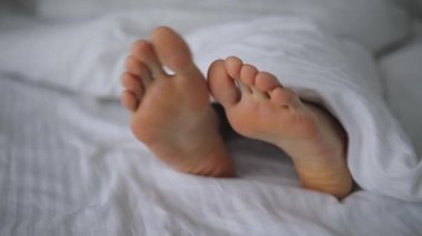 Yatakta battaniyenin altında dans eden erkek ayağı