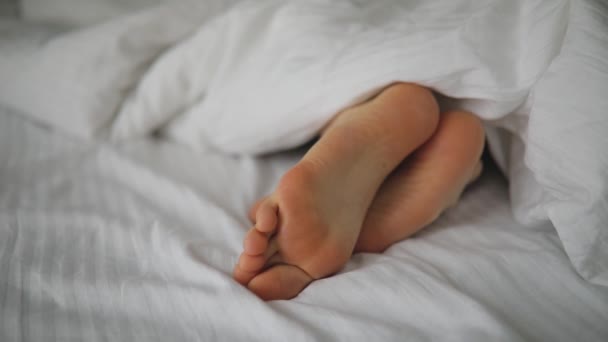 Muž nohy v posteli pod dekou — Stock video
