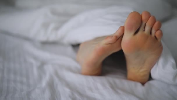 地球温暖化の男性が毛布の下ベッドを foots します。 — ストック動画
