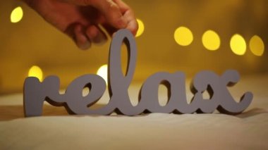 Word Relax bir yatakta sarı bulanık ışık bokeh arka plan ile silüeti