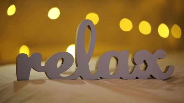 Silhouet van woord Relax op een bed met gele wazig lights bokeh achtergrond — Stockvideo