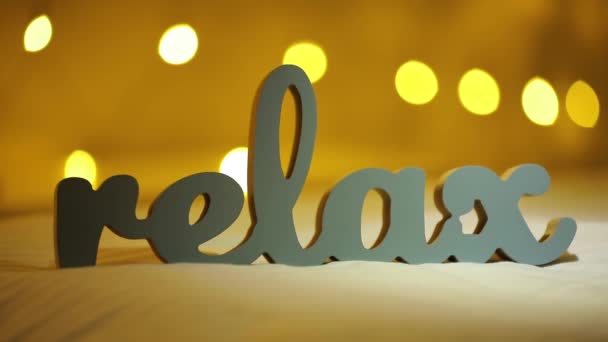 Silhouet van woord Relax op een bed met gele wazig lights bokeh achtergrond — Stockvideo