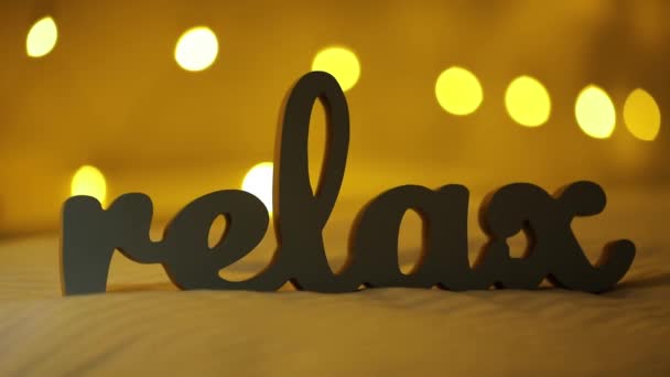 Silhouet van woord Relax op een bed met gele wazig lights bokeh achtergrond — Stockvideo