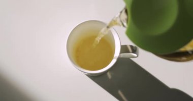 Pouring green tea into white cup, top view, included original audio