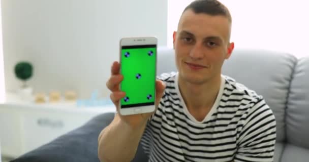 Muž ukazuje zelená obrazovka smartphone doma — Stock video